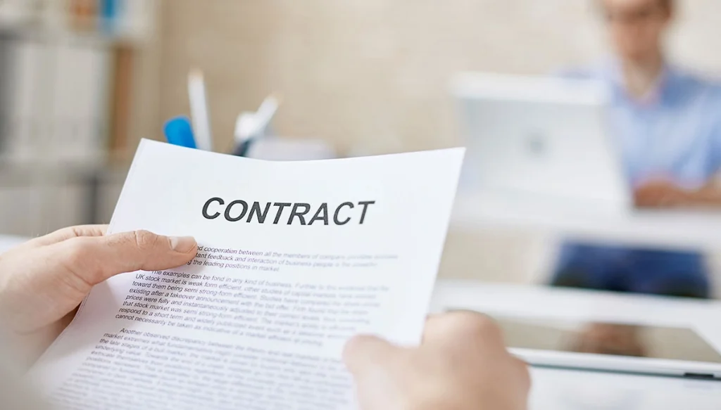 hands holding a contract across from another individual