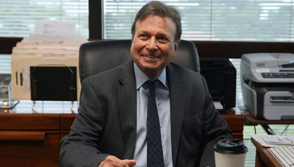 attorney smiling while sitting behind a desk