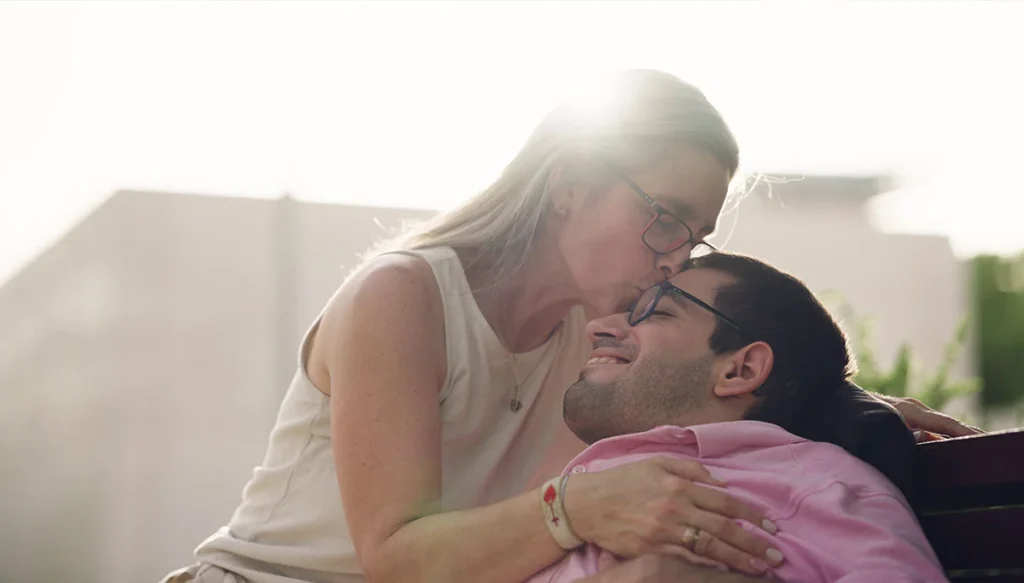 woman kissing a disabled man on the head.